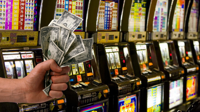 Row of Casino Slot Machines, Hand Holding Money Bills