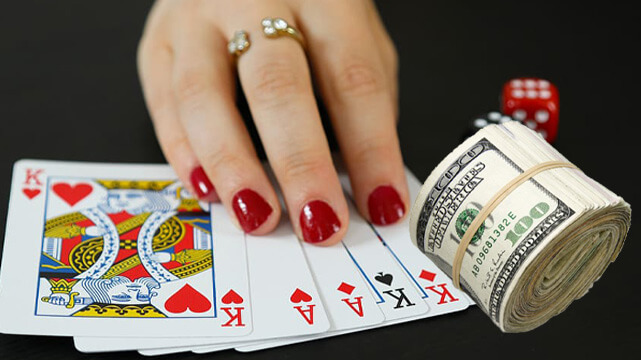 Hand Touching Poker Cards Spread Out, Roll of Money, Dice