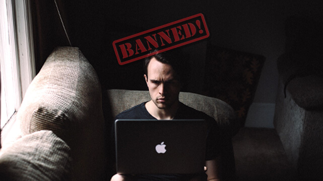 Guy Sitting on Couch With Laptop, Red Banned Logo