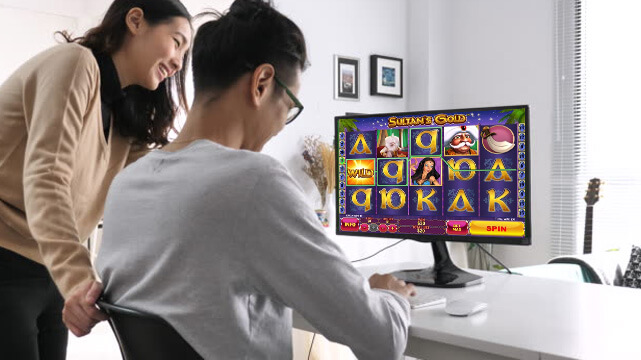 Two People Looking at Computer Displaying Online Slot Game