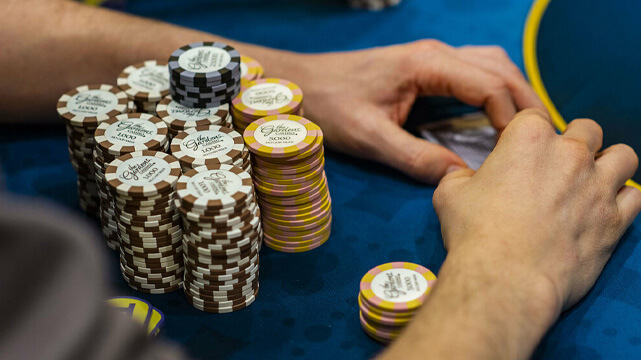 Hands on Poker Table Surrounded by Stacks of Casino Chips