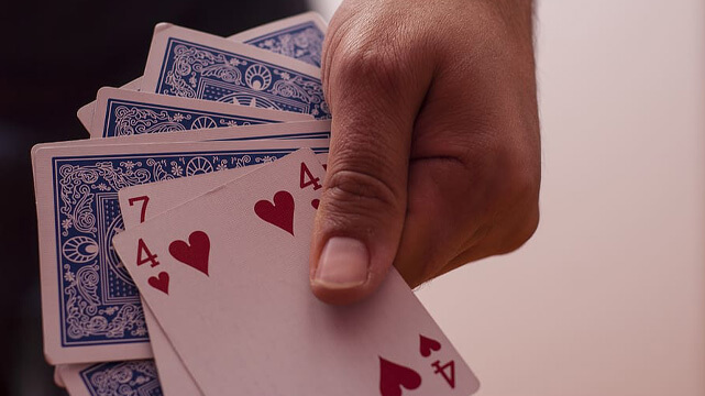 Hands Holding Onto Poker Cards Stack to the Side