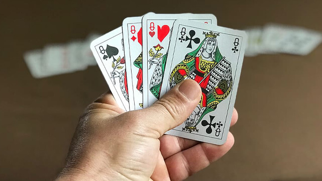 Hand Holding Poker Cards Over Table