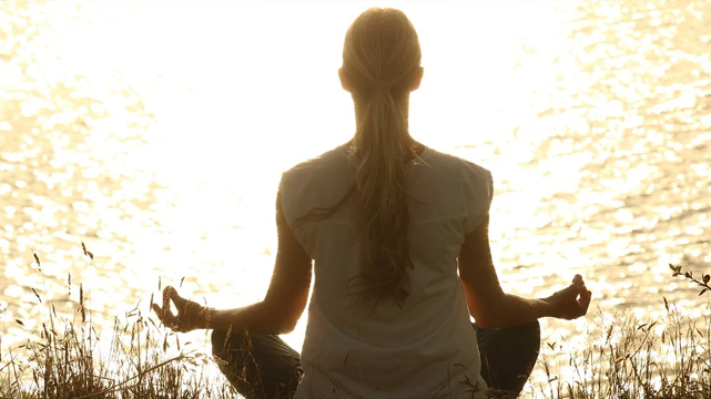 Woman Meditating Next to a Lake