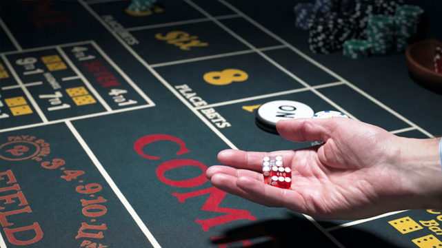 Person Holding Dice Over a Craps Table