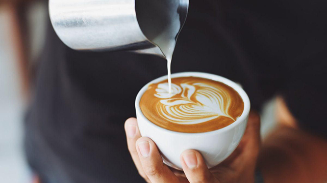 Barista Pouring Creamer Into A Cup Of Coffee