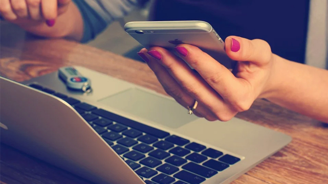 Wanita Menggunakan Laptop dan Ponselnya